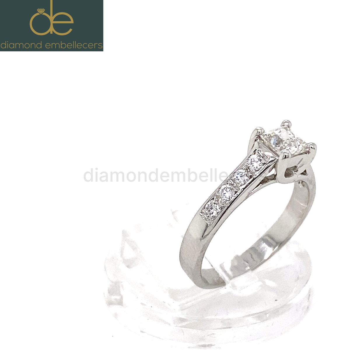 A platinum diamond ring with a square princess-cut centre stone and pavé-set side stones round brilliant diamond .