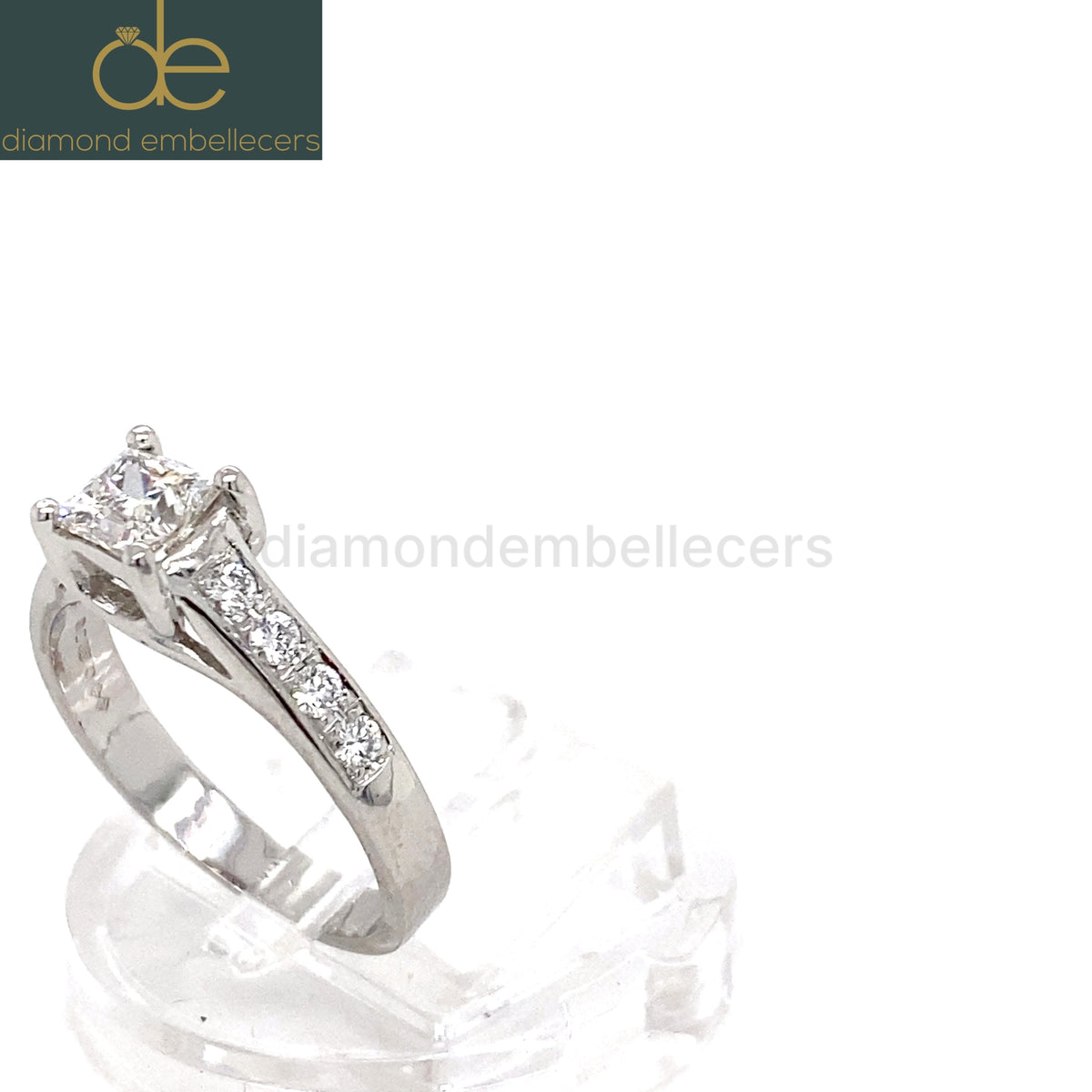 A platinum diamond ring with a square princess-cut centre stone and pavé-set side stones round brilliant diamond .